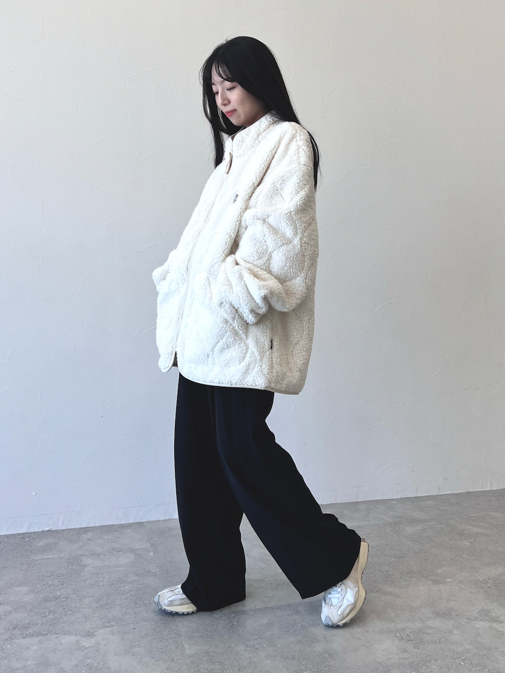 ブラック系のスラックス、ホワイト系のスニーカー、その他のブルゾンを着用したレディースの冬コーディネートの2枚目の写真