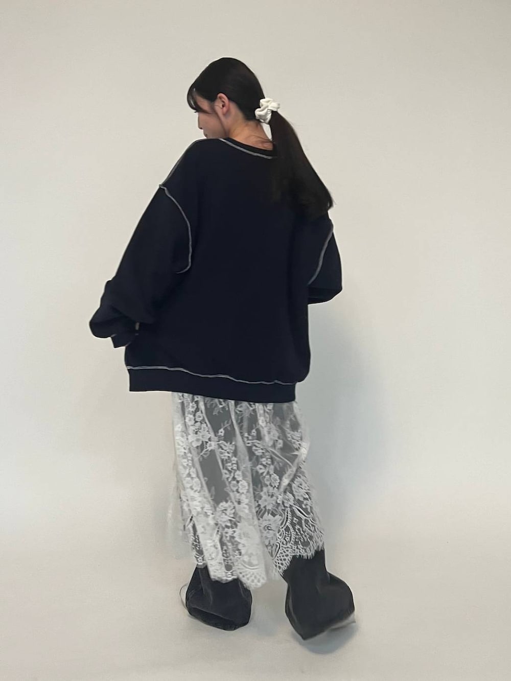 ブラック系のデニムパンツ、ブルー系のパーカー、ホワイト系のスニーカーを着用したレディースの冬コーディネートの4枚目の写真