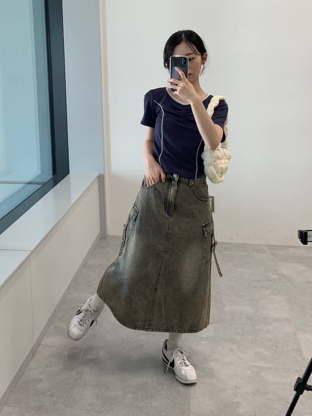 ブラック系のデニムスカート、ホワイト系のショルダーバッグ、ブルー系のTシャツ/カットソーを着用したレディースの夏コーディネートの3枚目の写真