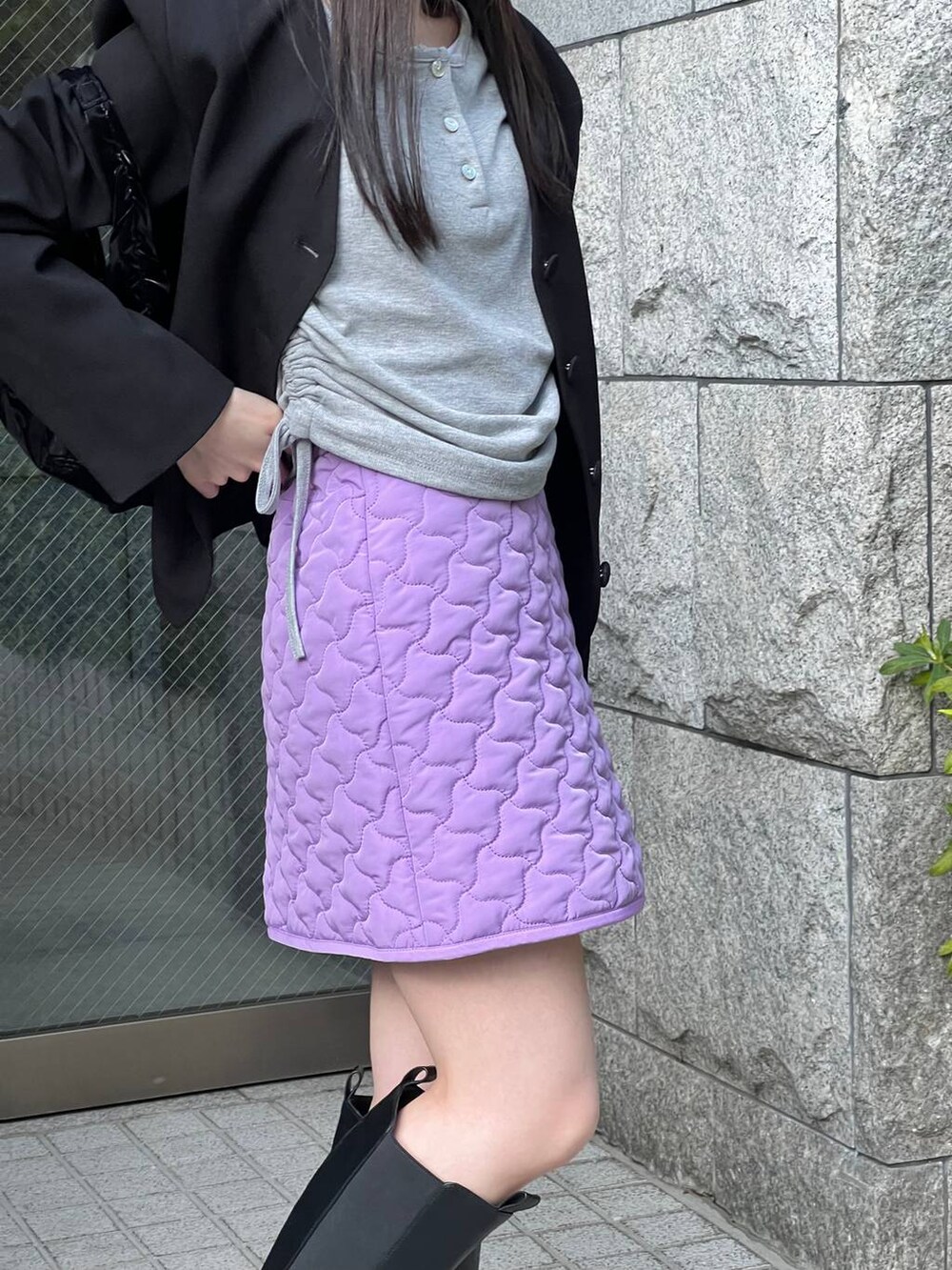 ブラック系のブーツ、パープル系のスカート、ブラック系のノーカラージャケットを着用したレディースの冬コーディネートの6枚目の写真