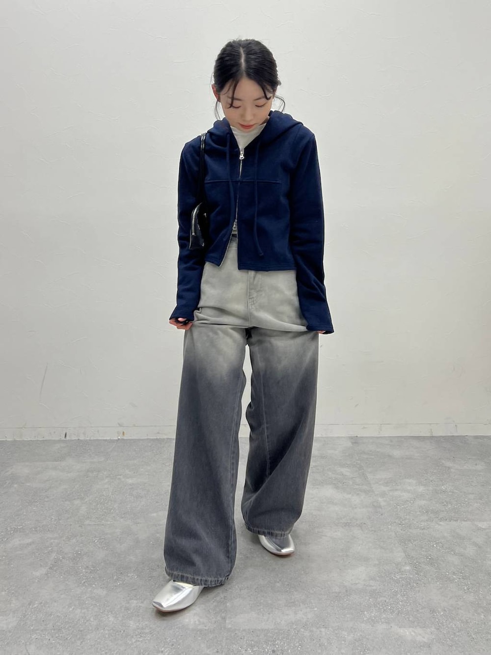 ブルー系のスウェット、ブラック系のデニムパンツ、ブラック系のハンドバッグを着用したレディースの冬コーディネートの2枚目の写真