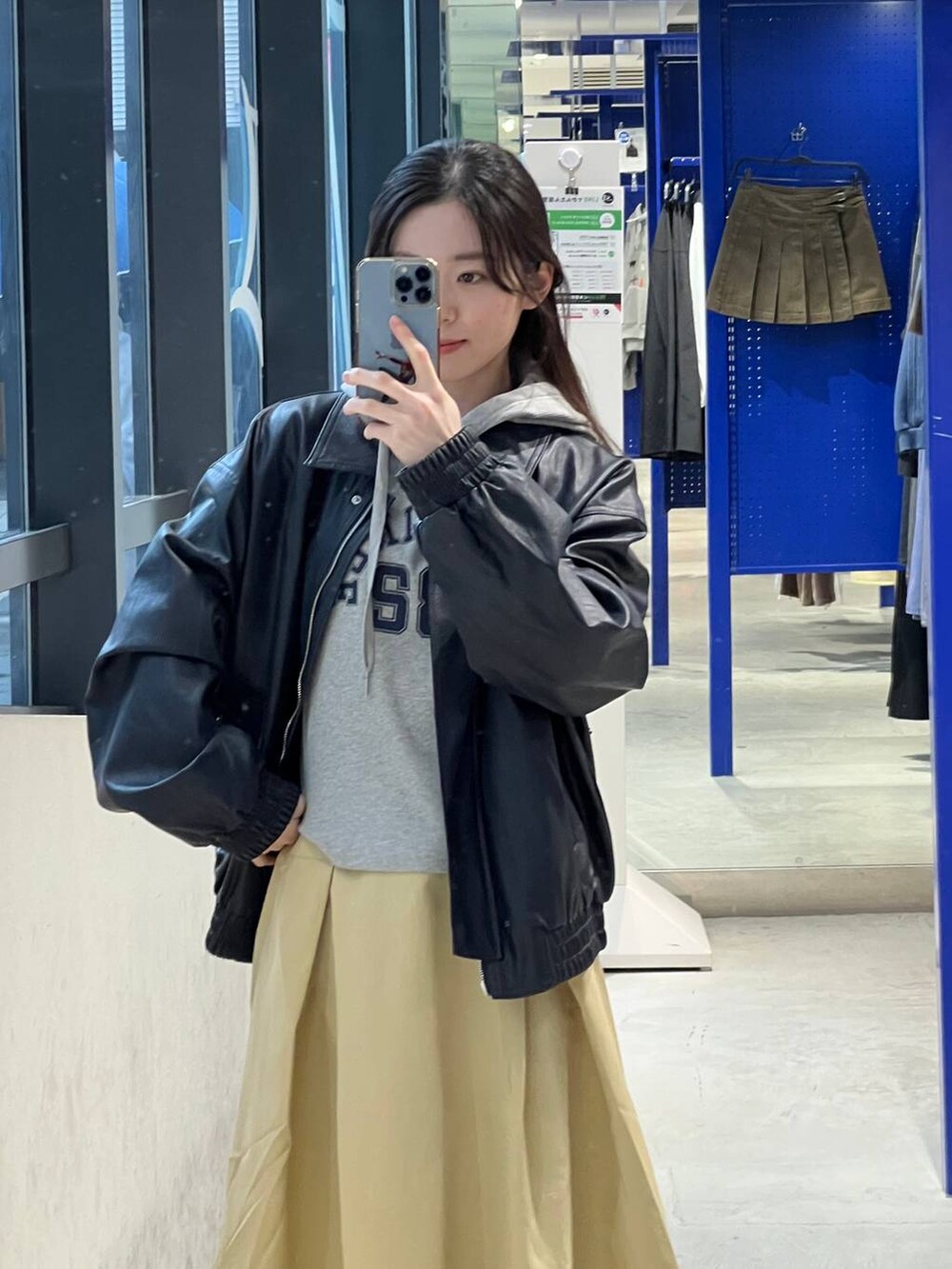 ベージュ系のスカート、ブルー系のブルゾン、グレー系のパーカーを着用したレディースの春コーディネートの6枚目の写真