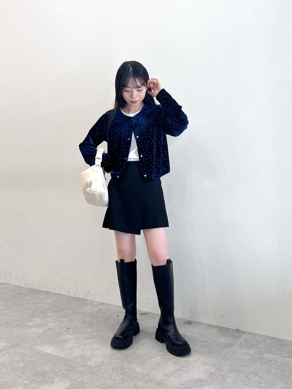 ブラック系のブーツ、ブラック系のスカート、ベージュ系のショルダーバッグを着用したレディースの冬コーディネートの2枚目の写真