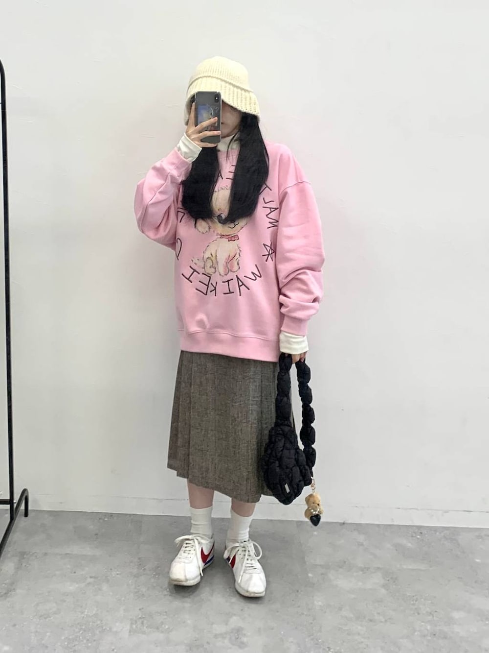 ブラック系のショルダーバッグ、ブラウン系のスカート、ピンク系のスウェットを着用したレディースの冬コーディネートの3枚目の写真