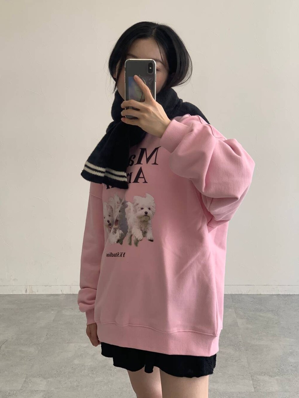 ブラック系のスカート、ピンク系のスウェット、ブラック系のマフラーを着用したレディースの秋コーディネートの6枚目の写真