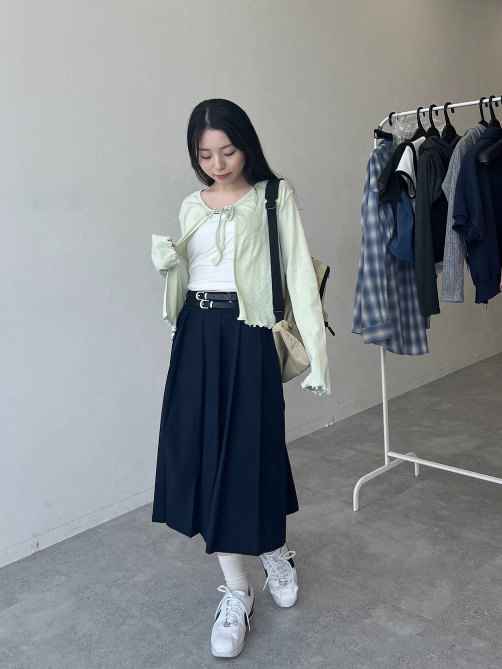 ベージュ系のバックパック/リュック、ブルー系のスカート、グリーン系のカーディガン/ボレロを着用したレディースの春コーディネートの3枚目の写真