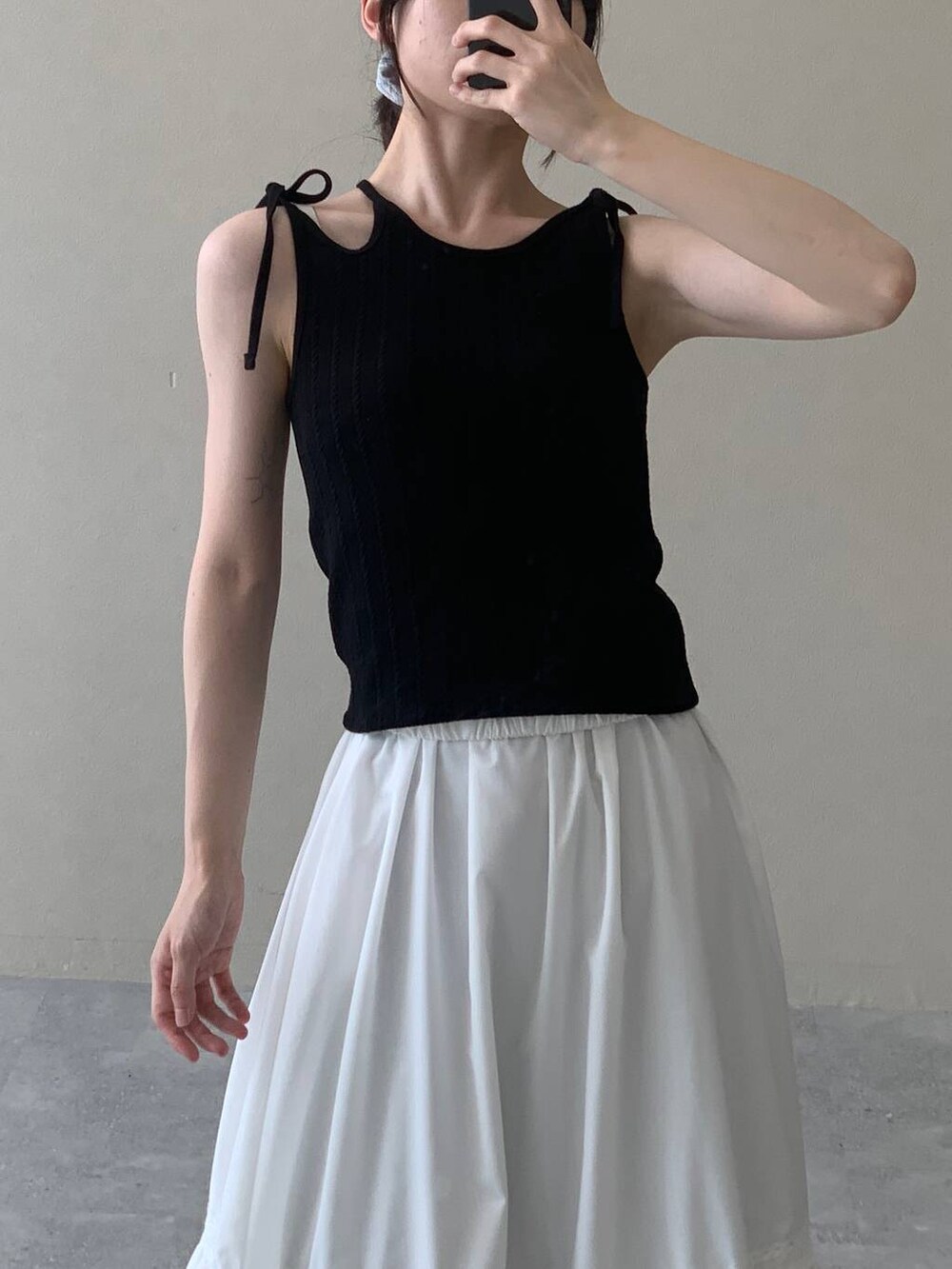 ホワイト系のスカート、ブラック系のキャミソールを着用したレディースの夏コーディネートの7枚目の写真