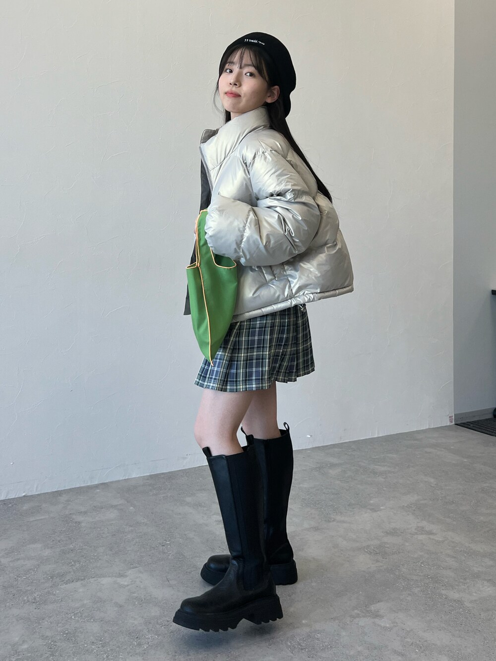 グリーン系のトートバッグ、その他のダウンジャケット/コート、ブラック系のブーツを着用したレディースの秋コーディネートの2枚目の写真