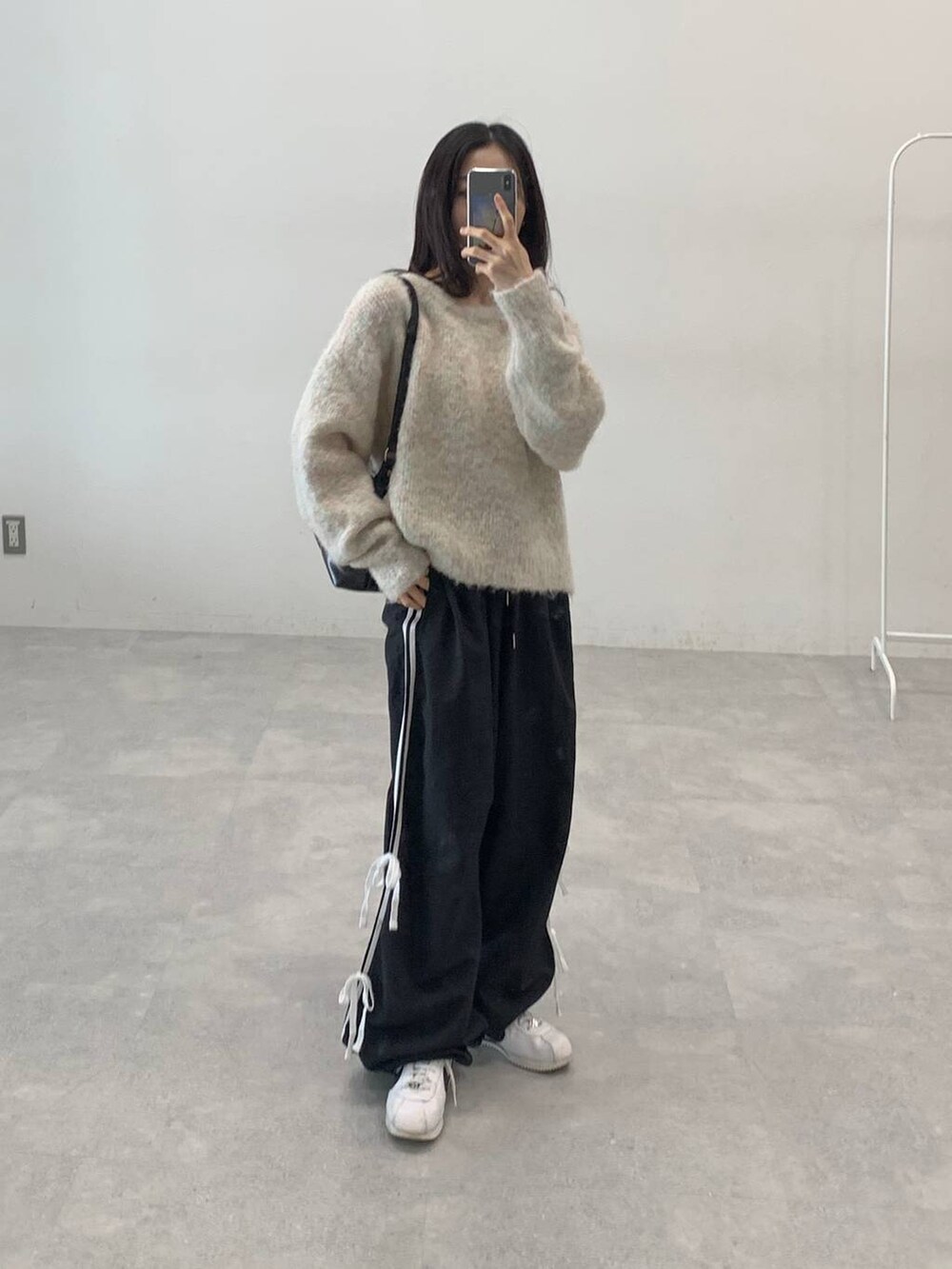 ブラック系のその他パンツ、ホワイト系のニット/セーター、ブラック系のハンドバッグを着用したレディースの秋コーディネートの3枚目の写真