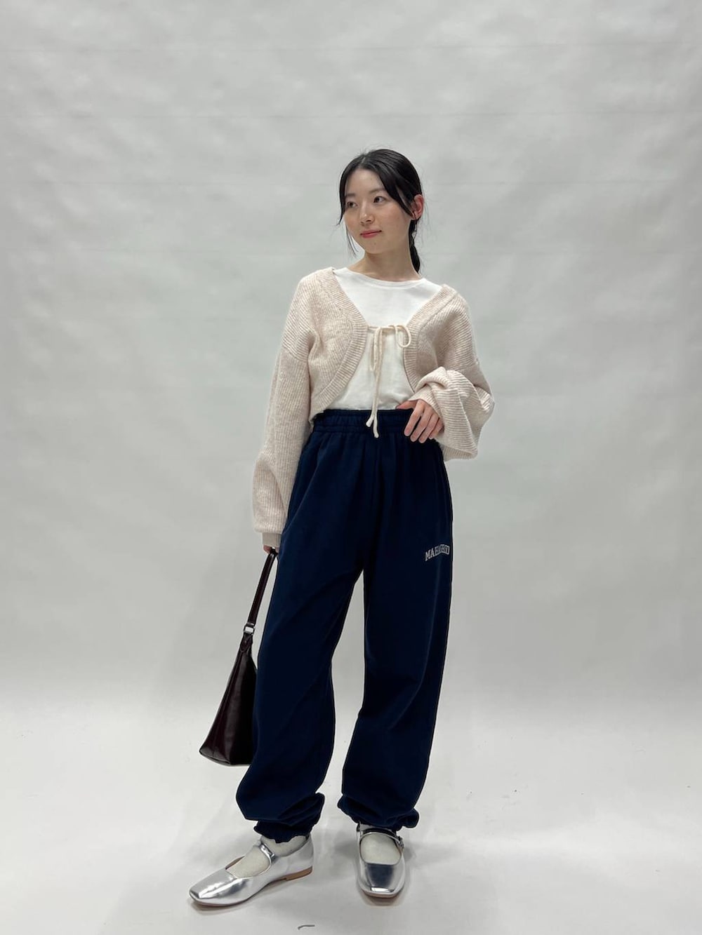 ブラック系のスウェットパンツ、ピンク系のカーディガン/ボレロ、ブラウン系のバッグを着用したレディースの冬コーディネートの2枚目の写真