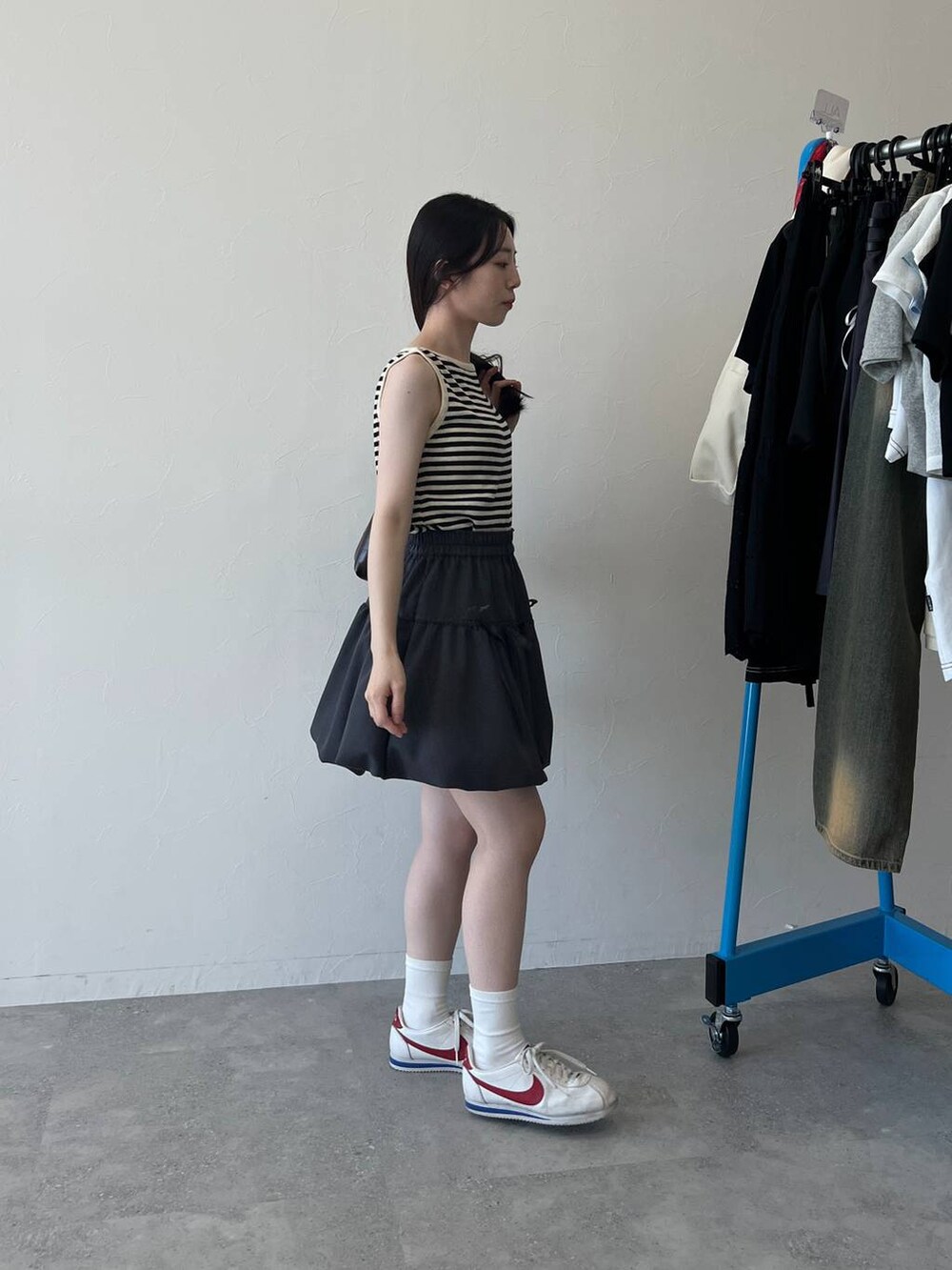 ベージュ系のTシャツ/カットソー、ベージュ系のショルダーバッグ、グレー系のスカートを着用したレディースの春コーディネートの5枚目の写真