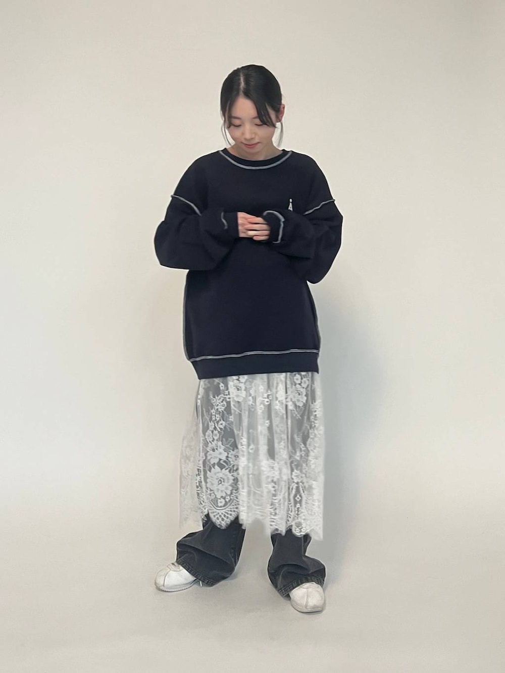 ブラック系のデニムパンツ、ブルー系のパーカー、ホワイト系のスニーカーを着用したレディースの冬コーディネートの6枚目の写真