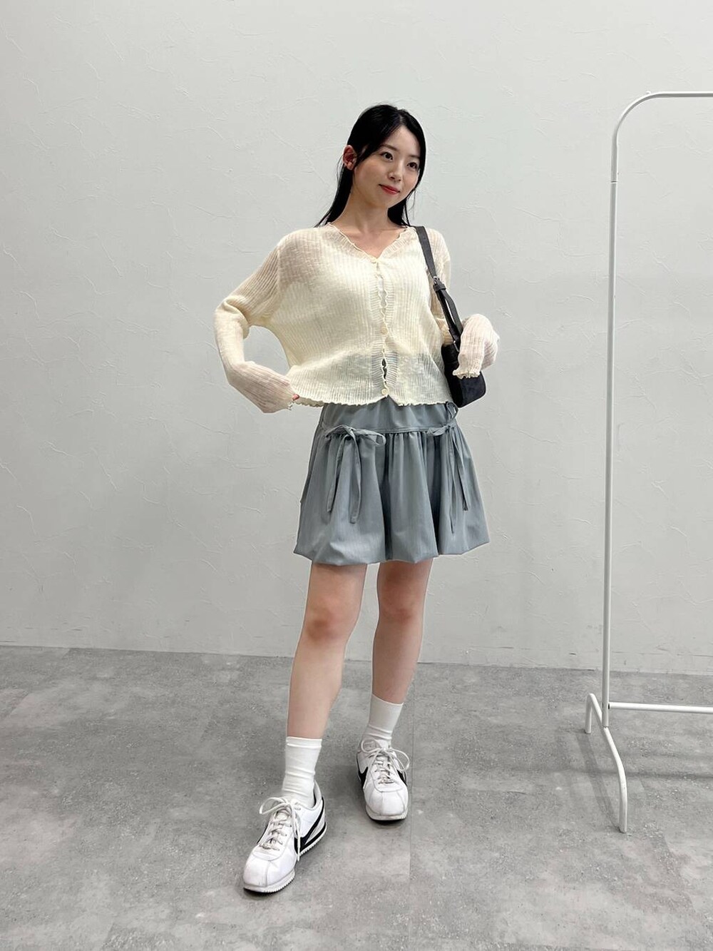 グレー系のスカート、ブラック系のトートバッグ、ベージュ系のカーディガン/ボレロを着用したレディースの夏コーディネートの2枚目の写真