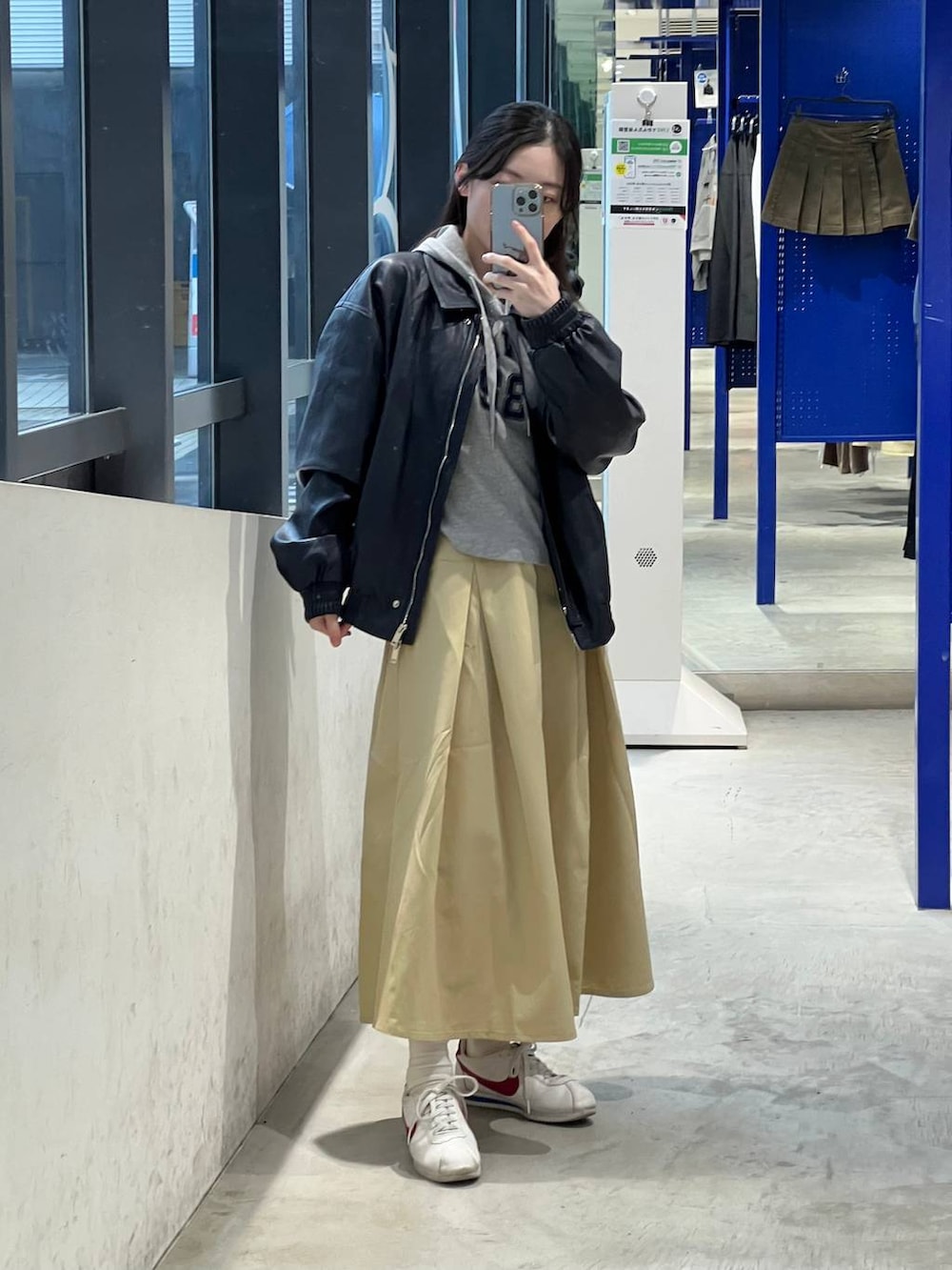 ベージュ系のスカート、ブルー系のブルゾン、グレー系のパーカーを着用したレディースの春コーディネートの2枚目の写真