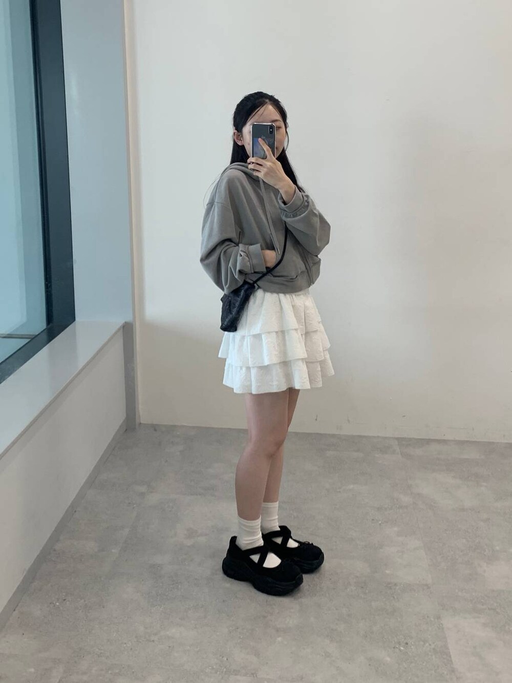 グレー系のパーカー、ホワイト系のスカートを着用したレディースの秋コーディネートの4枚目の写真