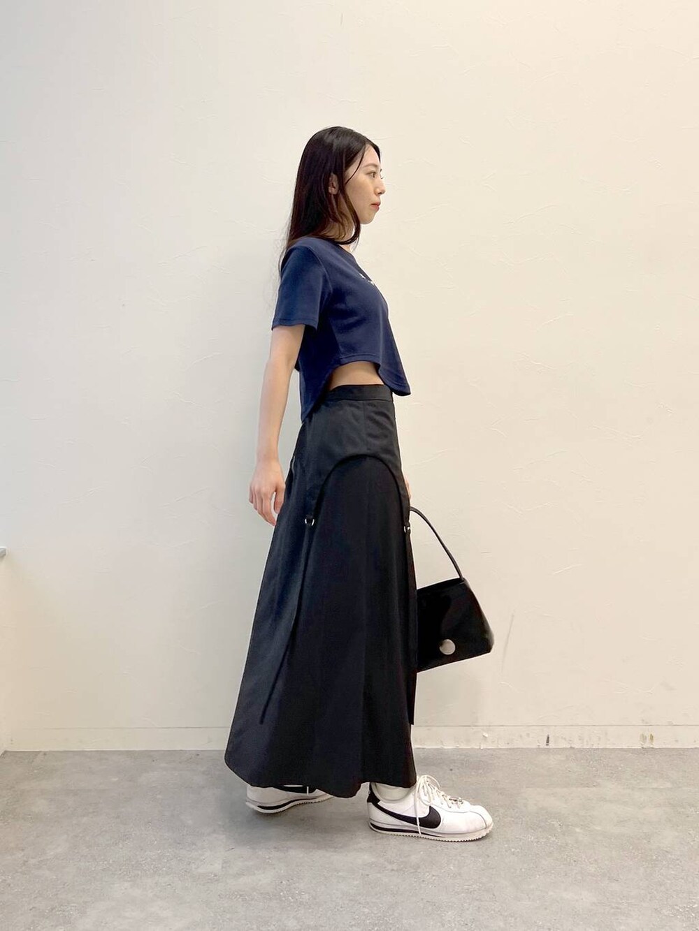 グレー系のスカート、ブラック系のハンドバッグ、ブルー系のTシャツ/カットソーを着用したレディースの夏コーディネートの4枚目の写真