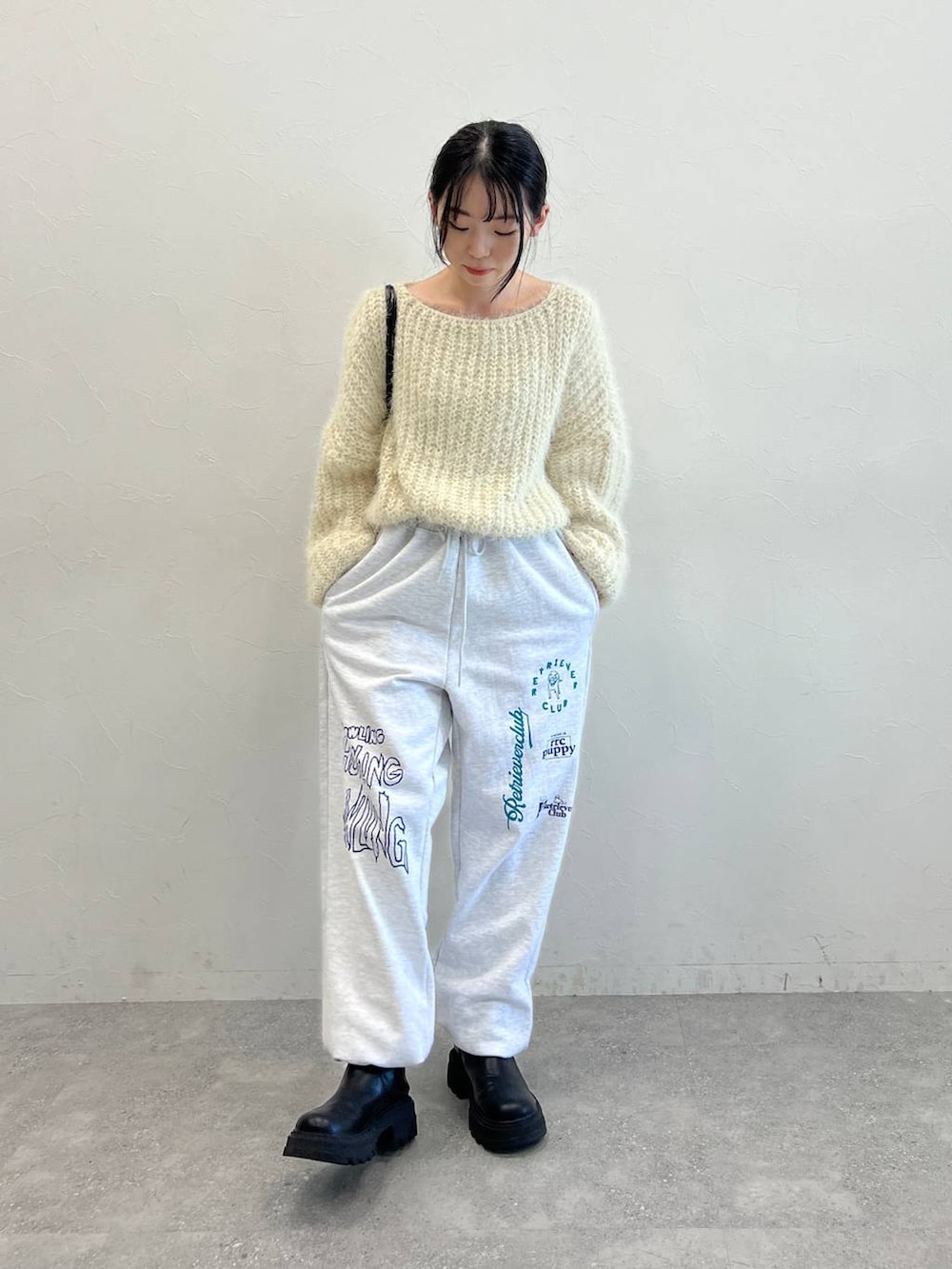 ブラック系のブーツ、ブラック系のショルダーバッグ、ベージュ系のニット/セーターを着用したレディースの冬コーディネートの2枚目の写真