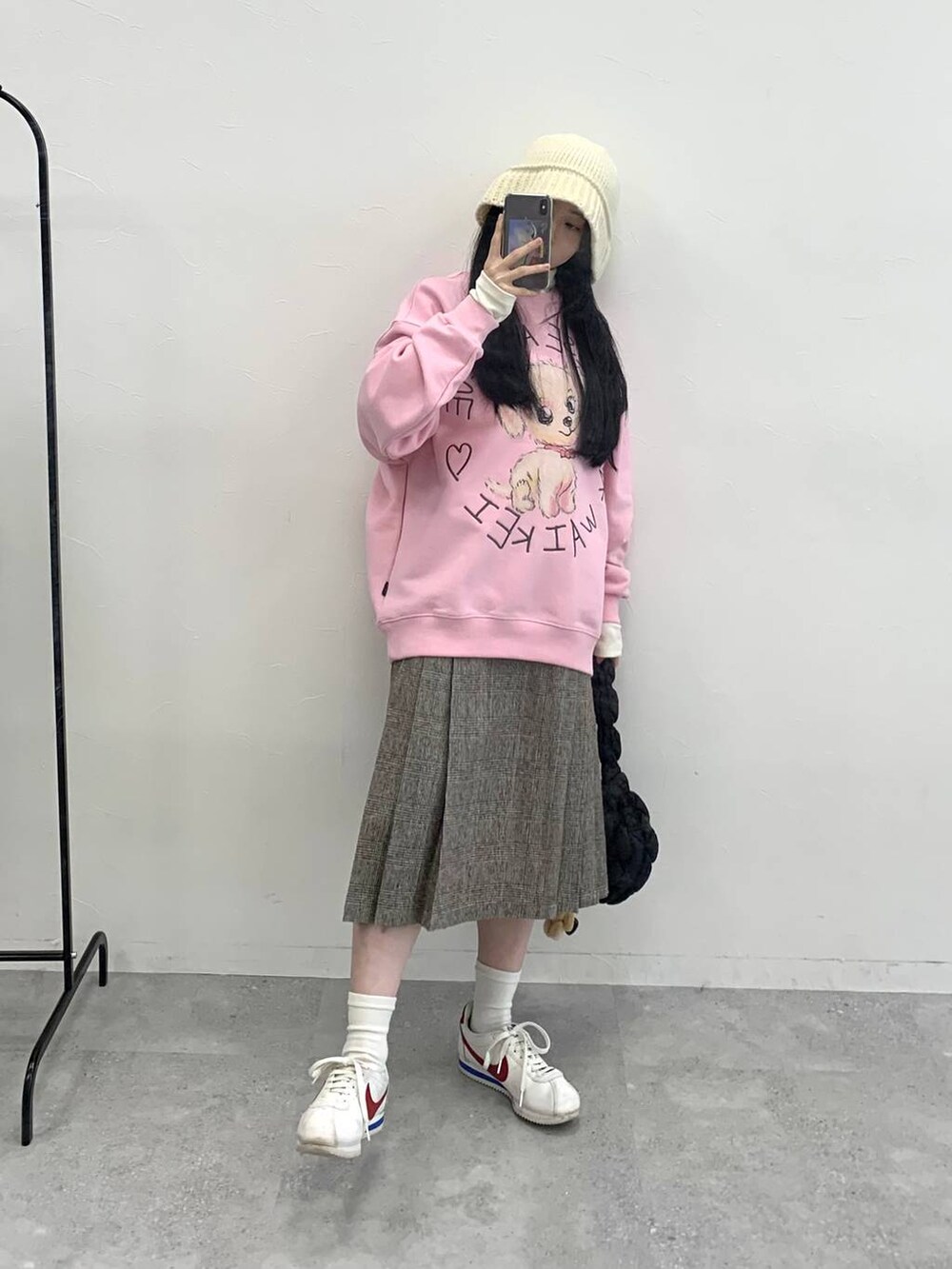 ブラック系のショルダーバッグ、ブラウン系のスカート、ピンク系のスウェットを着用したレディースの冬コーディネートの2枚目の写真