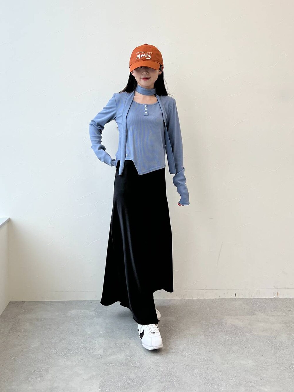 ブラック系のスカート、ブルー系のTシャツ/カットソー、ブラウン系のキャップを着用したレディースの春コーディネートの2枚目の写真