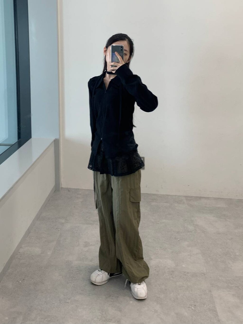 グリーン系のカーゴパンツ、ブラック系のスカート、ブラック系のTシャツ/カットソーを着用したレディースの秋コーディネートの2枚目の写真