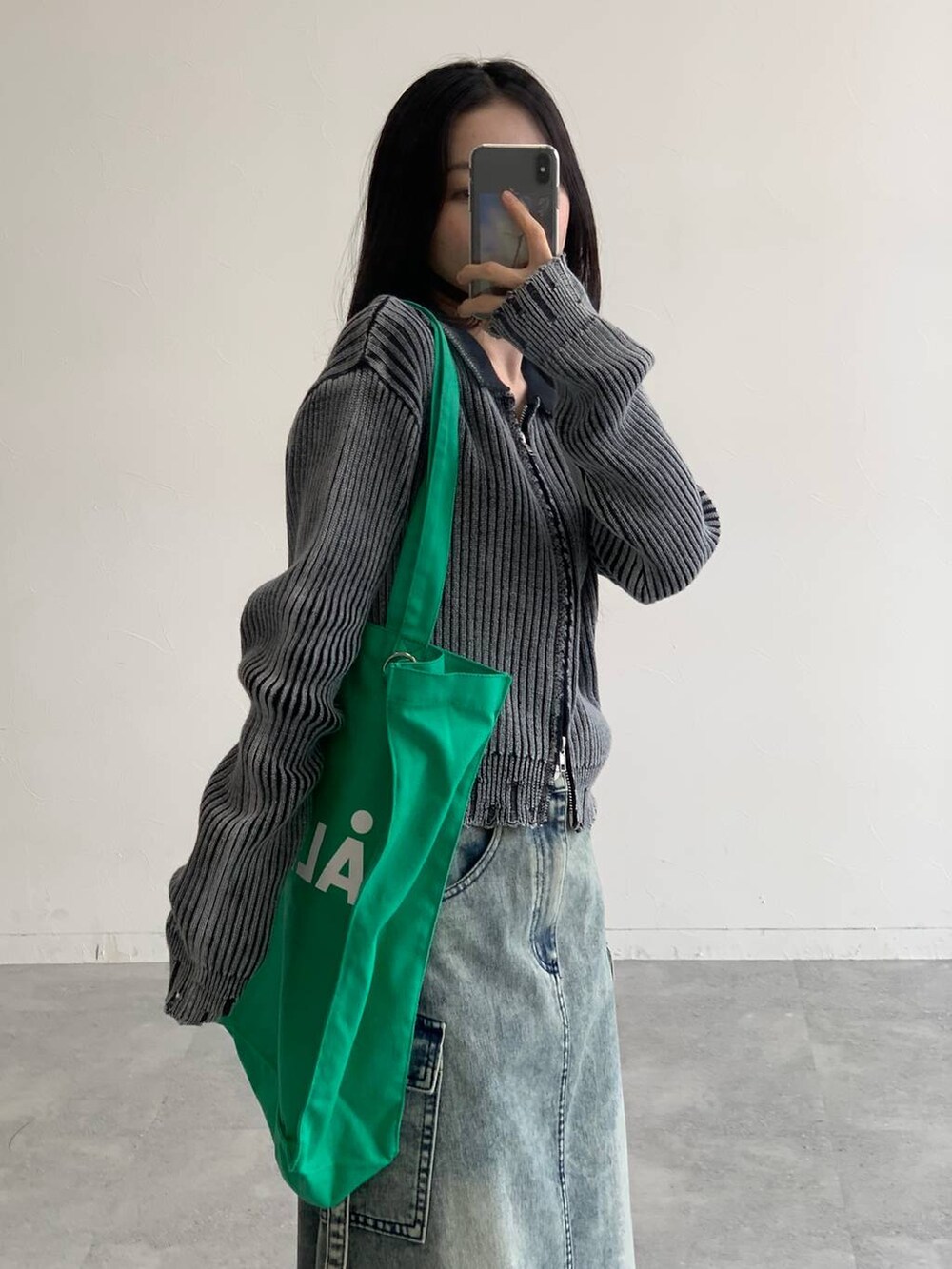 ブルー系のデニムスカート、グリーン系のトートバッグ、ブラック系のニット/セーターを着用したレディースの秋コーディネートの6枚目の写真