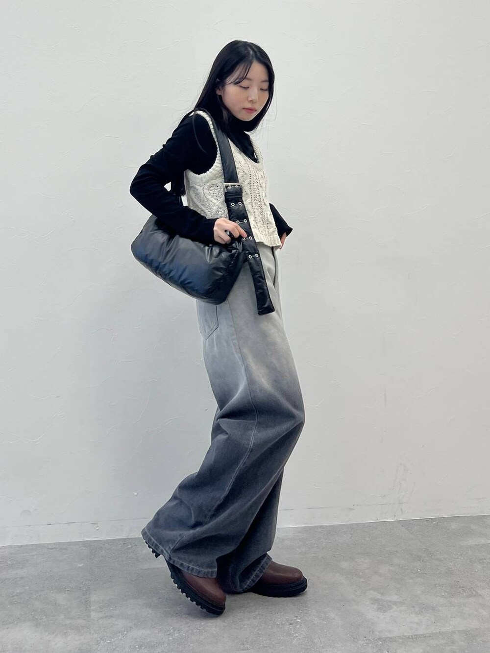 ブラック系のショルダーバッグ、ブラック系のデニムパンツ、ベージュ系のベストを着用したレディースの冬コーディネートの5枚目の写真