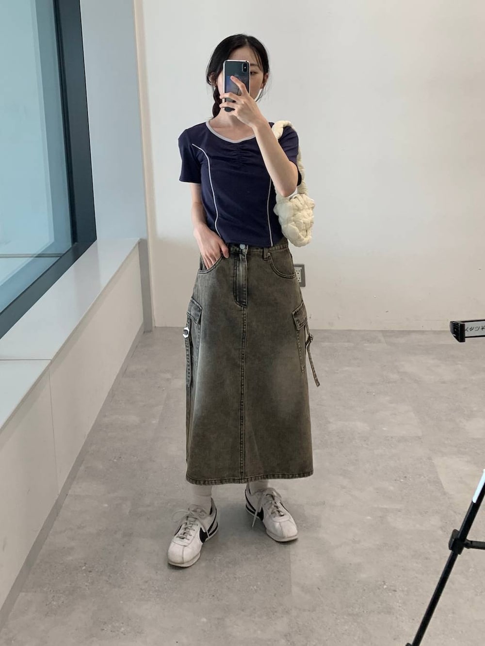 ブラック系のデニムスカート、ホワイト系のショルダーバッグ、ブルー系のTシャツ/カットソーを着用したレディースの夏コーディネートの4枚目の写真