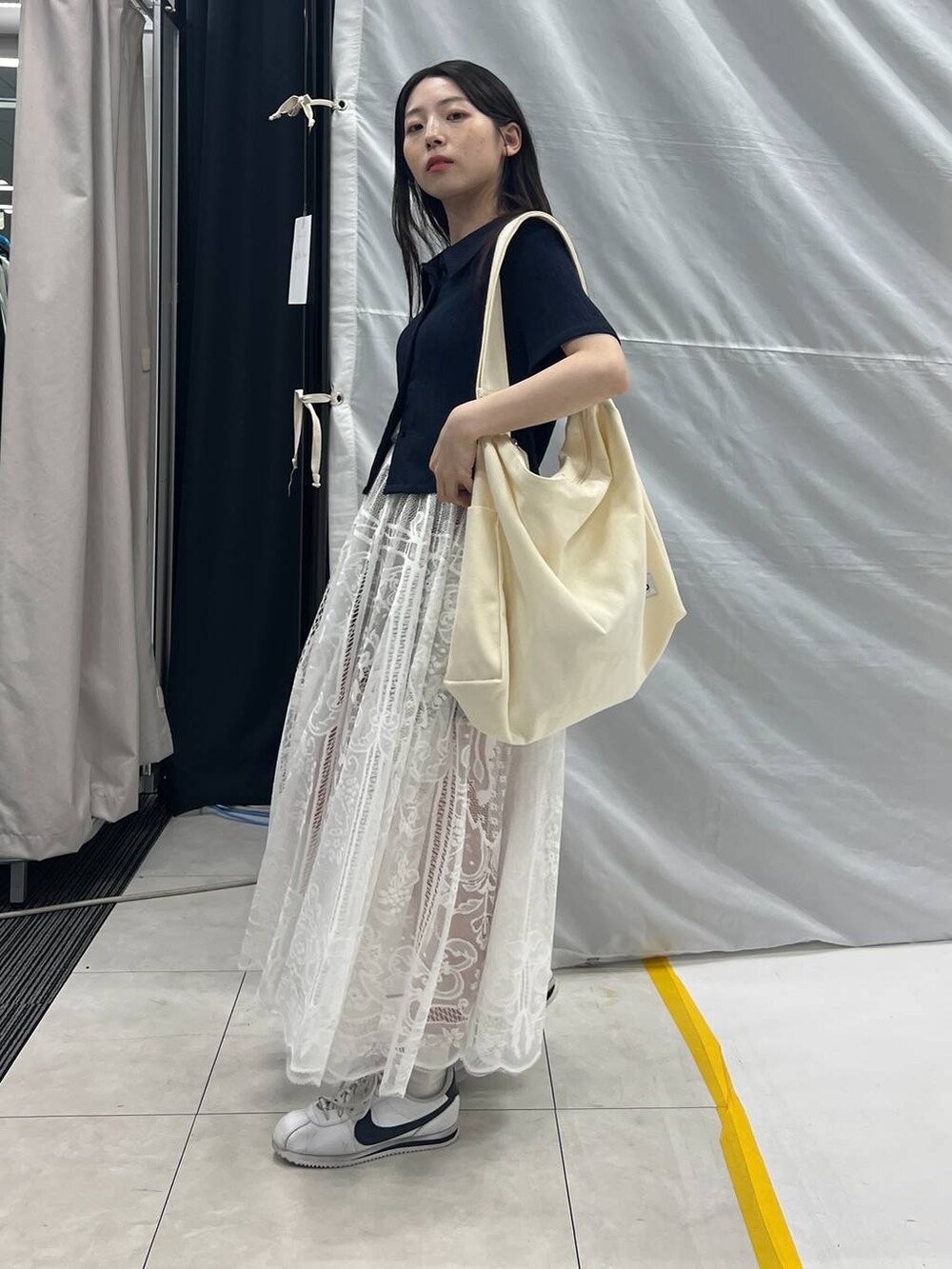 ホワイト系のスカート、ベージュ系のショルダーバッグ、グレー系のデニムパンツを着用したレディースの夏コーディネートの2枚目の写真