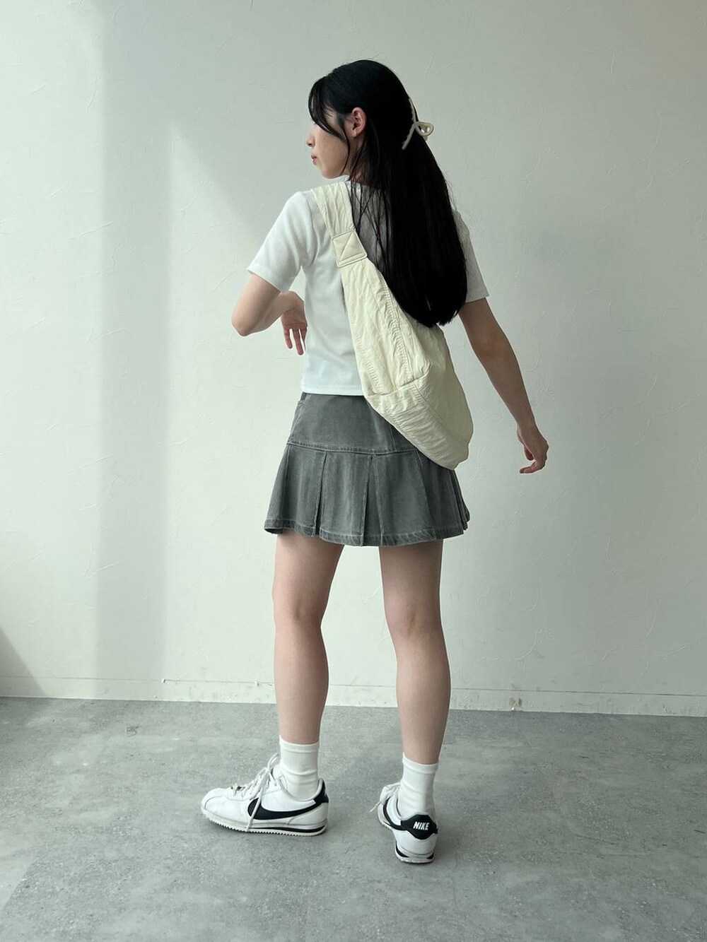 ベージュ系のショルダーバッグ、ホワイト系のTシャツ/カットソー、グレー系のデニムスカートを着用したレディースの夏コーディネートの4枚目の写真