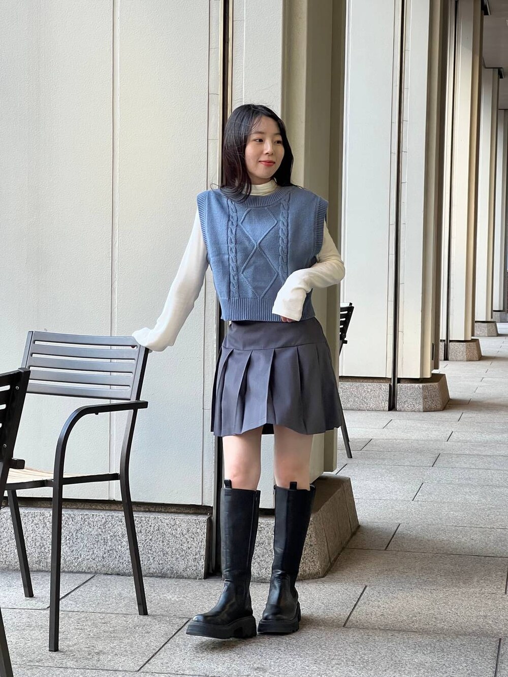 ブルー系のベスト、ブラック系のブーツ、ベージュ系のTシャツ/カットソーを着用したレディースの冬コーディネートの3枚目の写真