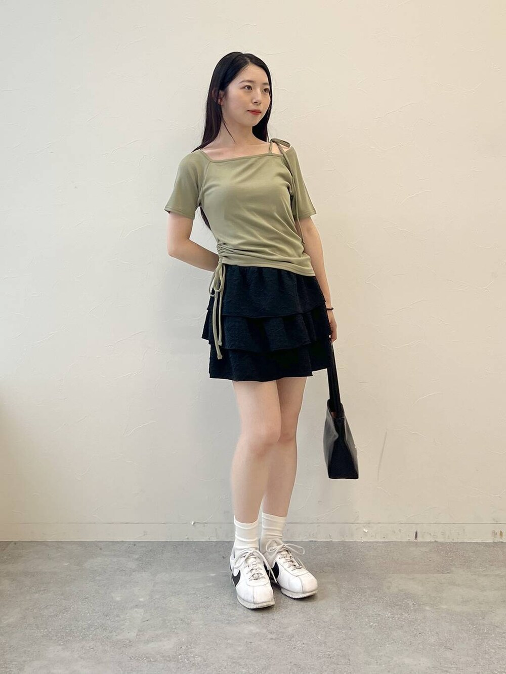 グリーン系のTシャツ/カットソー、ブラック系のハンドバッグ、ブラック系のスカートを着用したレディースの夏コーディネートの5枚目の写真