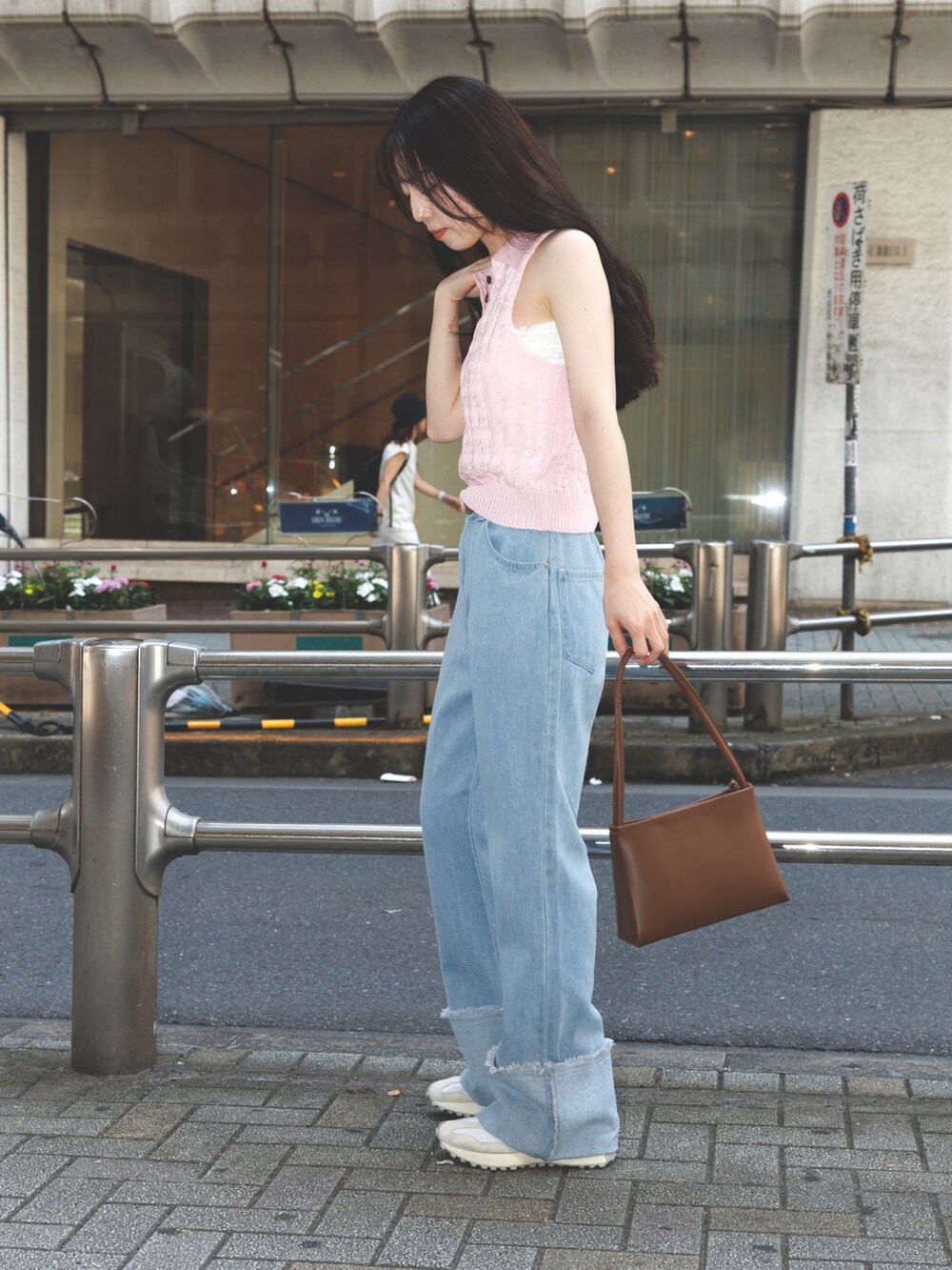 ブルー系のデニムパンツ、ピンク系のニット/セーター、ブラウン系のショルダーバッグを着用したレディースの夏コーディネートの2枚目の写真