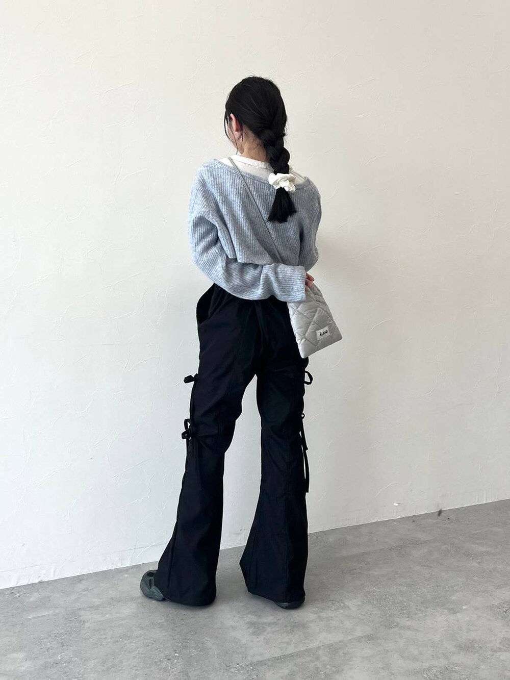 グレー系のショルダーバッグ、ベージュ系のTシャツ/カットソー、ブラック系のスラックスを着用したレディースの冬コーディネートの4枚目の写真