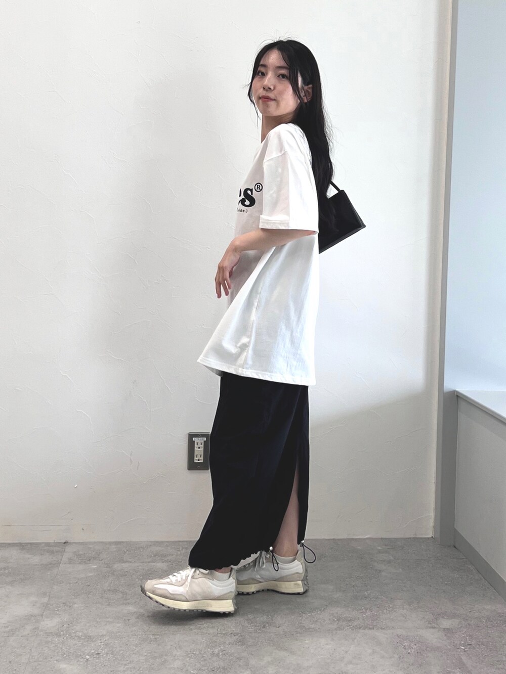 ホワイト系のTシャツ/カットソー、ブラック系のスカート、ホワイト系のスニーカーを着用したレディースの夏コーディネートの2枚目の写真