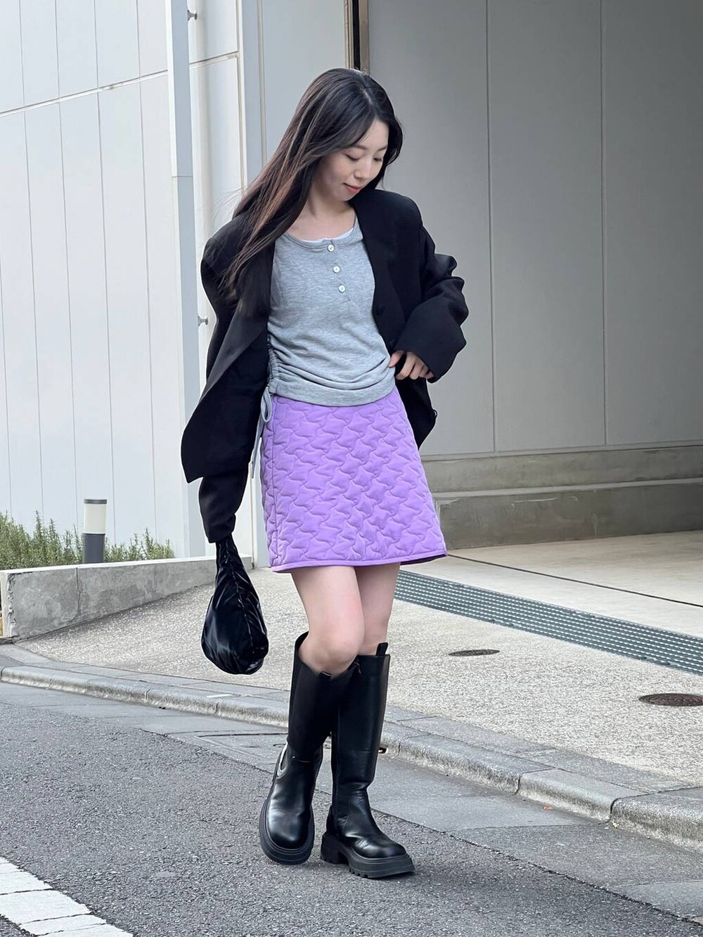 ブラック系のブーツ、パープル系のスカート、ブラック系のノーカラージャケットを着用したレディースの冬コーディネートの2枚目の写真