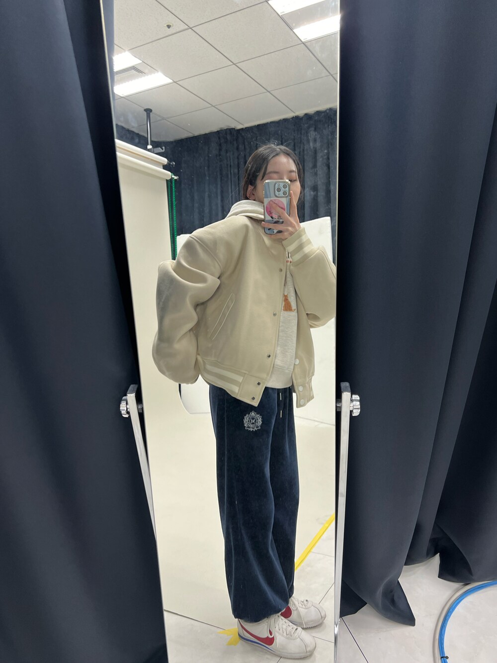 ベージュ系のパーカー、ベージュ系のブルゾン、ブルー系のスウェットパンツを着用したレディースの冬コーディネートの2枚目の写真