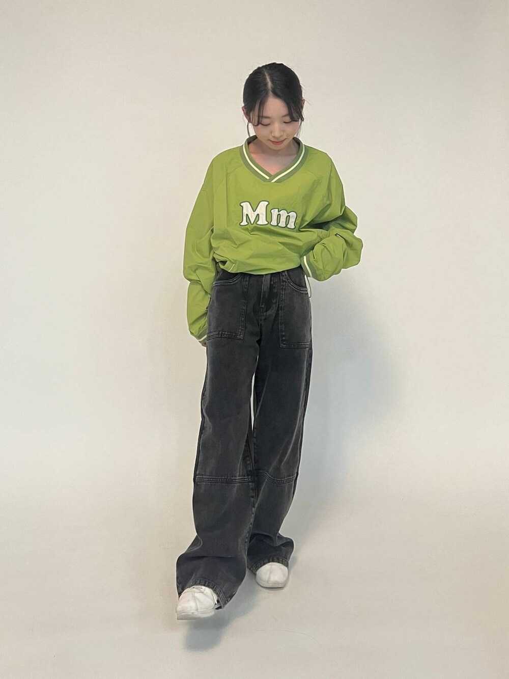 グリーン系のTシャツ/カットソー、ホワイト系のスニーカー、ブラック系のデニムパンツを着用したレディースの冬コーディネートの4枚目の写真