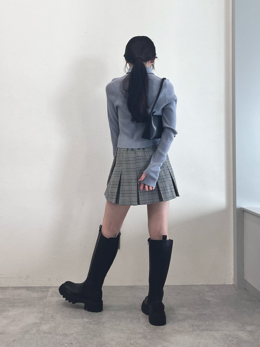ブラック系のブーツ、グレー系のスカート、ブルー系のニット/セーターを着用したレディースの冬コーディネートの3枚目の写真