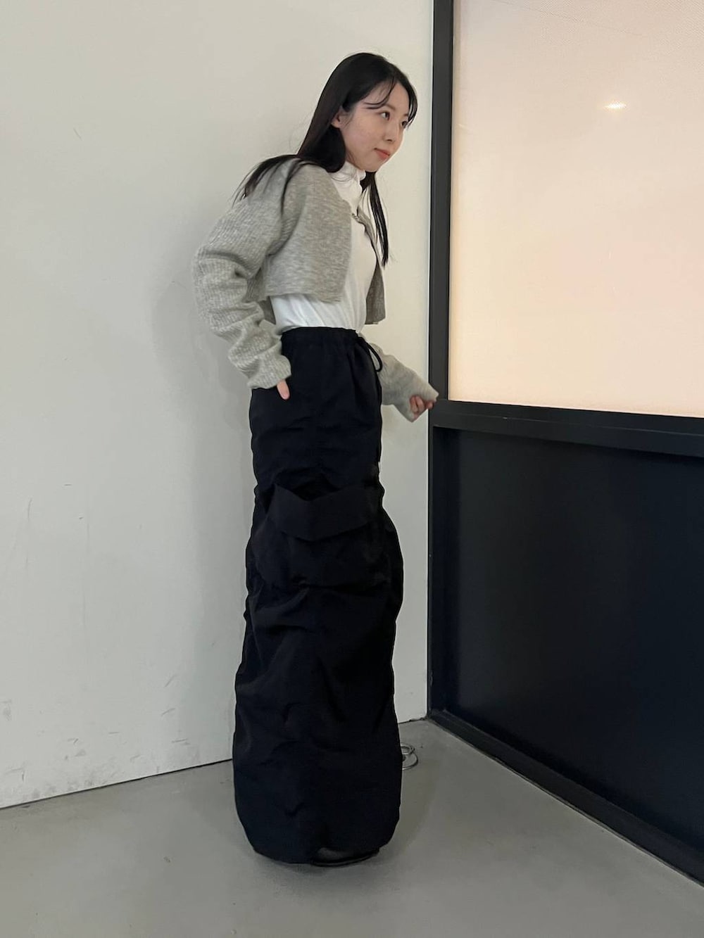 ブラック系のブーツ、ブラック系のスカート、グレー系のカーディガン/ボレロを着用したレディースの冬コーディネートの6枚目の写真
