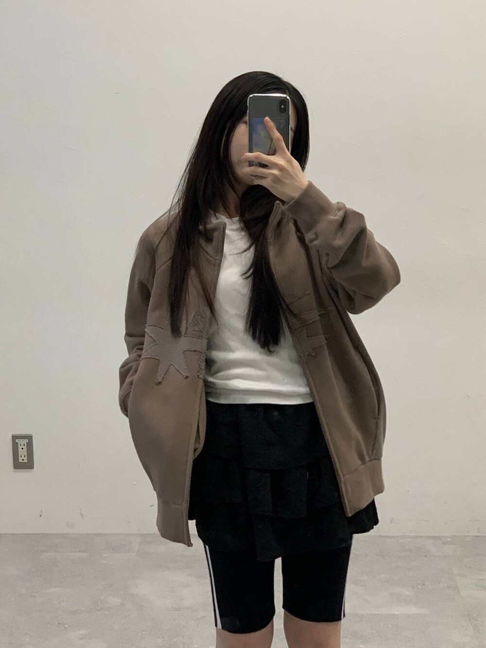 ブラック系のスカート、ベージュ系のパーカー、ブラック系のその他パンツを着用したレディースの秋コーディネートの5枚目の写真