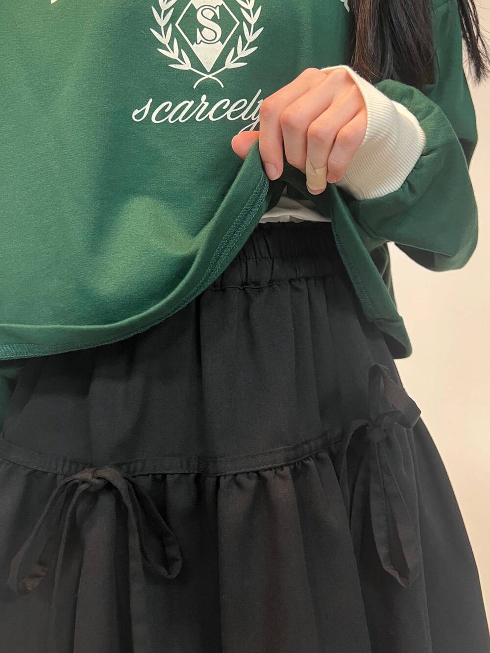 ブラック系のスカート、グリーン系のスウェットを着用したレディースの春コーディネートの4枚目の写真