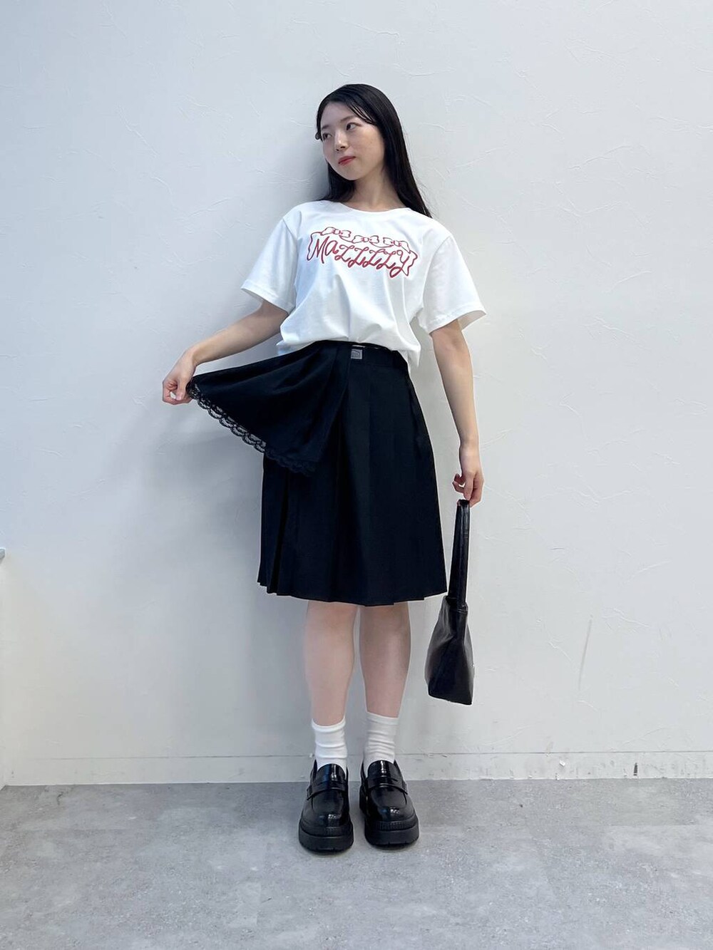 ブラック系のスカート、ホワイト系のTシャツ/カットソー、ブラック系のハンドバッグを着用したレディースの夏コーディネートの7枚目の写真