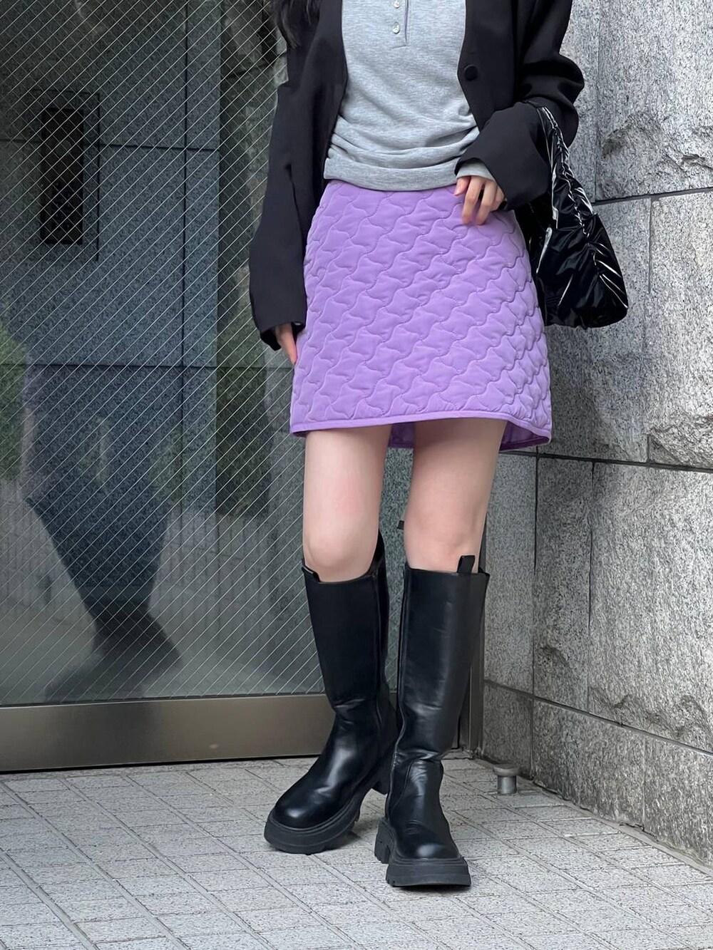 ブラック系のブーツ、パープル系のスカート、ブラック系のノーカラージャケットを着用したレディースの冬コーディネートの8枚目の写真