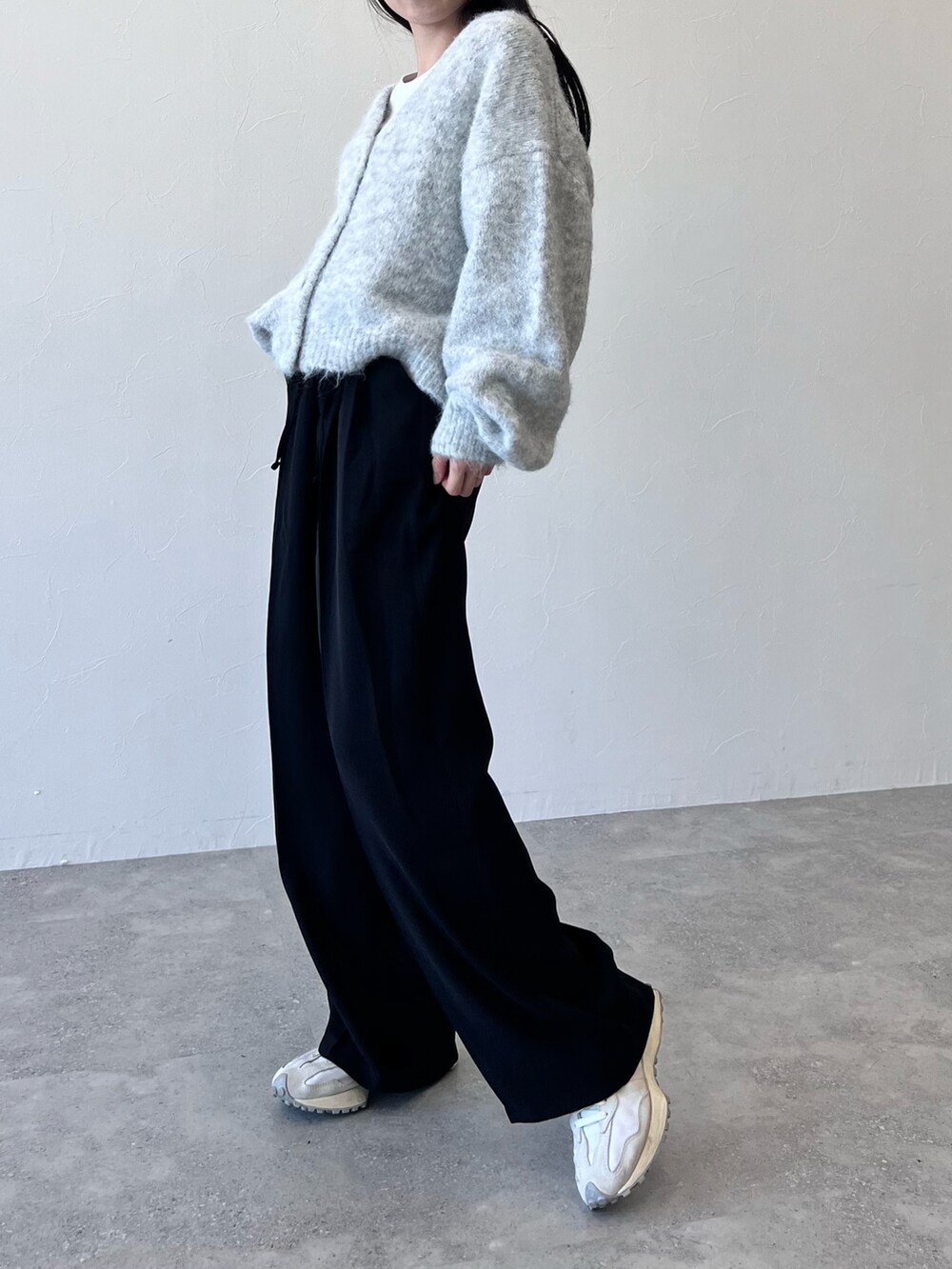 ホワイト系のスニーカー、ブラック系のスラックス、グレー系のカーディガン/ボレロを着用したレディースの冬コーディネートの2枚目の写真