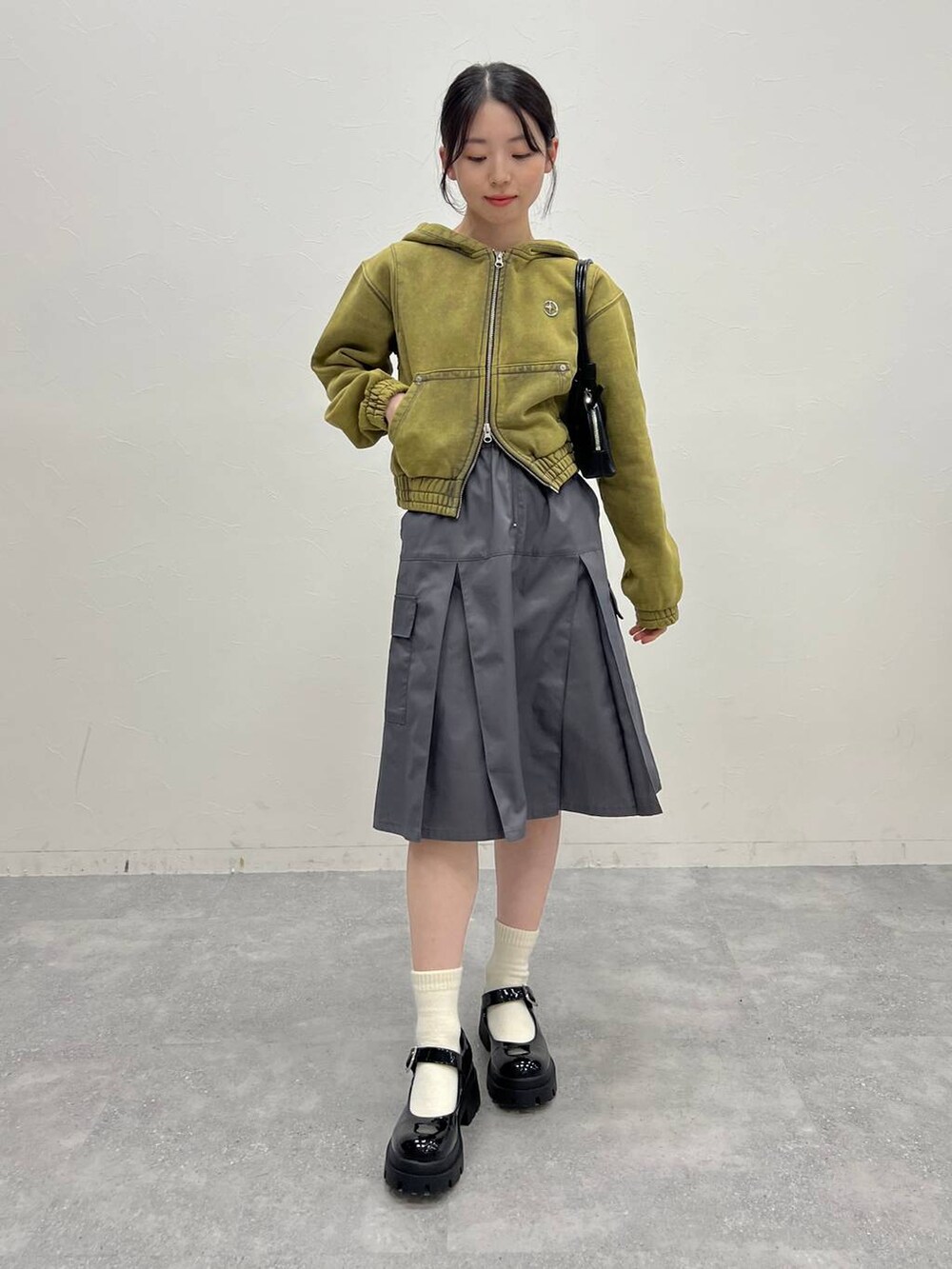 グレー系のスカート、ブラック系のローファー、グリーン系のパーカーを着用したレディースの冬コーディネートの7枚目の写真