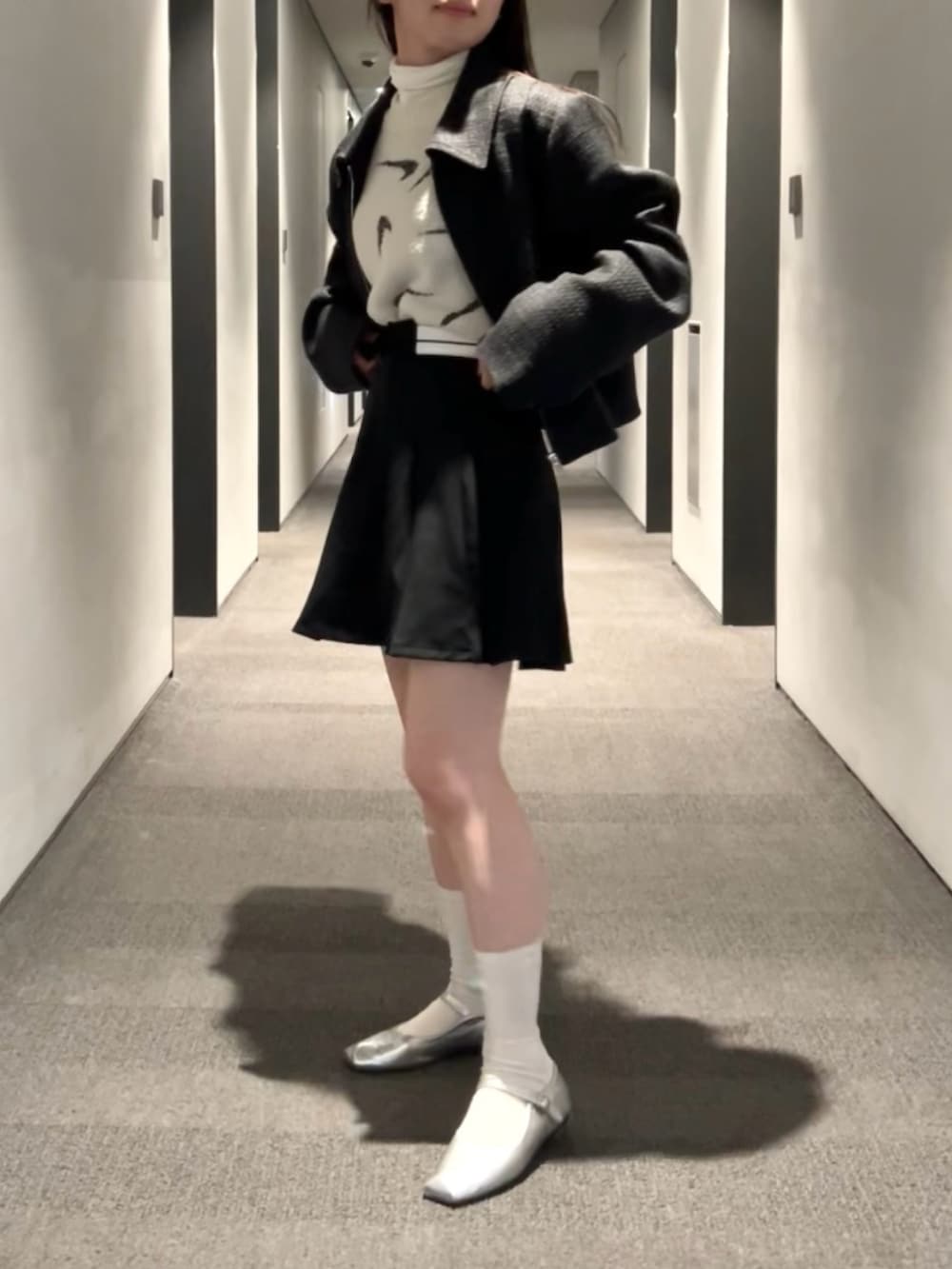 ブラック系のスカート、ブラック系のブルゾン、ブラウン系のTシャツ/カットソーを着用したレディースの春コーディネートの4枚目の写真