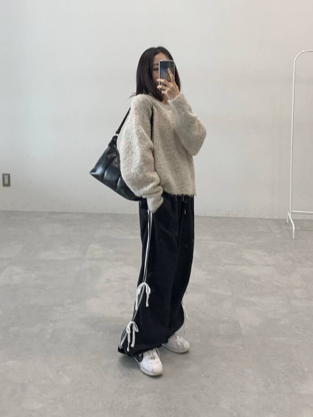 ブラック系のその他パンツ、ホワイト系のニット/セーター、ブラック系のハンドバッグを着用したレディースの秋コーディネートの4枚目の写真