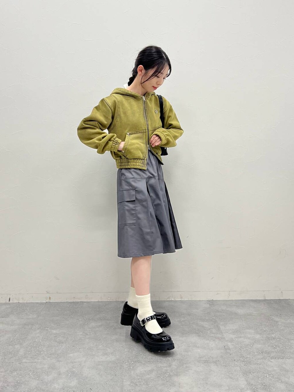 グレー系のスカート、ブラック系のローファー、グリーン系のパーカーを着用したレディースの冬コーディネートの6枚目の写真