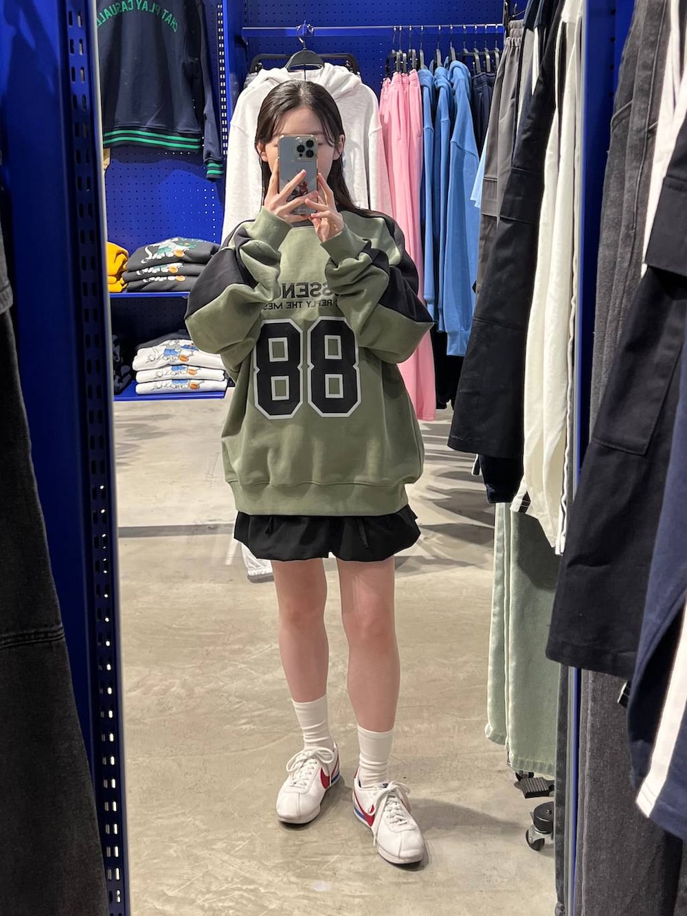 ブラック系のスカート、グリーン系のスウェットを着用したレディースの春コーディネートの4枚目の写真