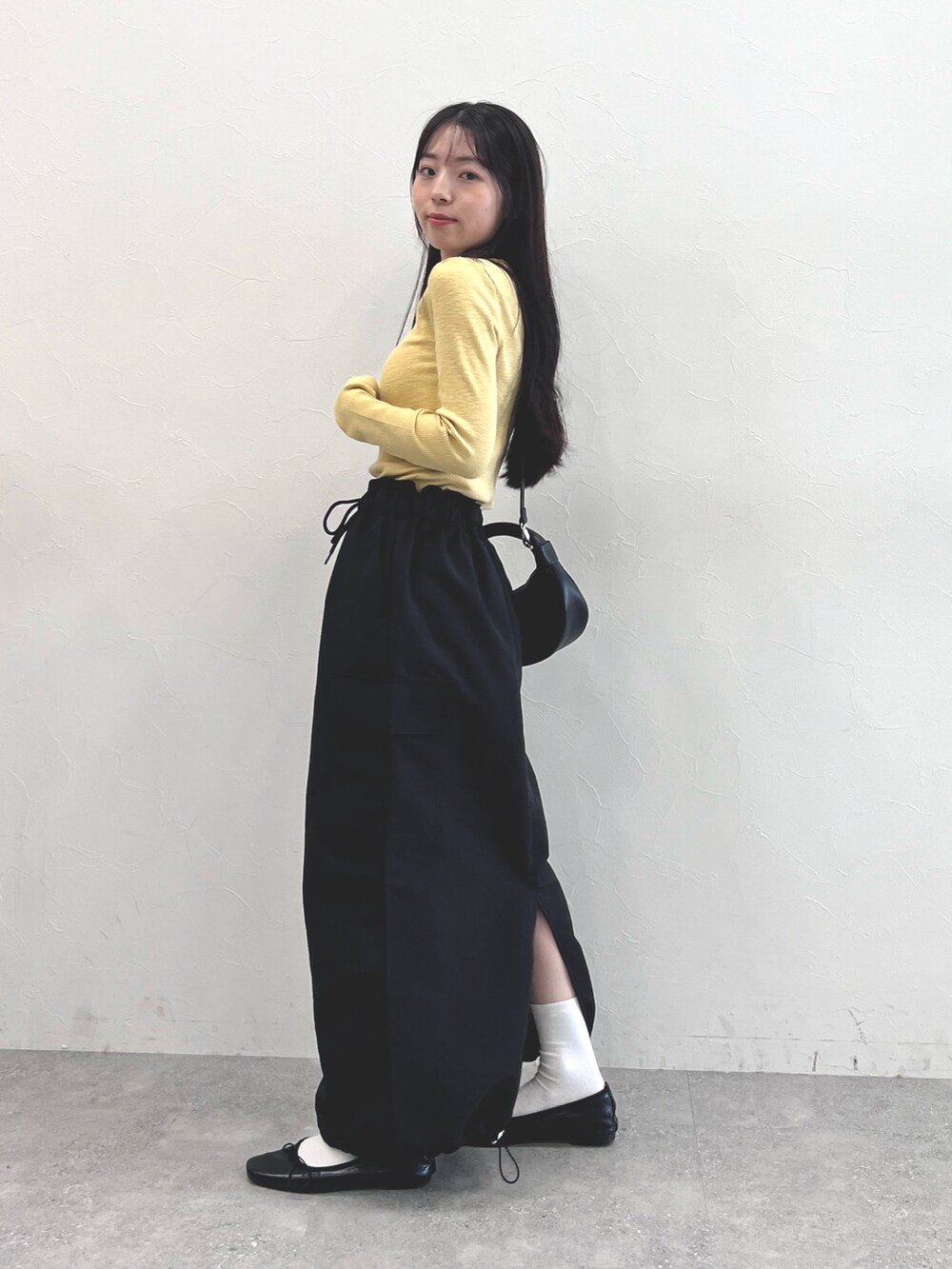 イエロー系のTシャツ/カットソー、ブラック系のショルダーバッグ、ブラック系のスカートを着用したレディースの秋コーディネートの2枚目の写真